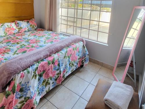 a bedroom with a bed with a floral bedspread and a window at ENTIRE LUXURY APARTMENTS in Mbabane