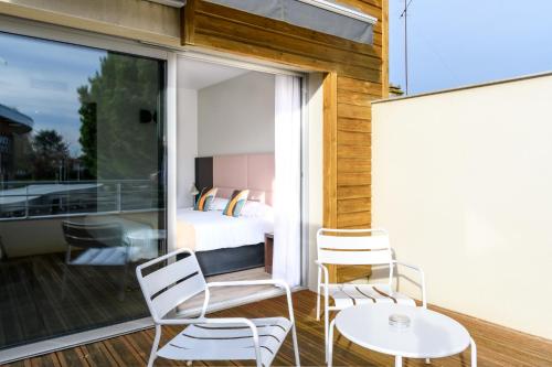 ビスカロッスにあるHype Hôtelのベッド、テーブル、椅子が備わる客室です。