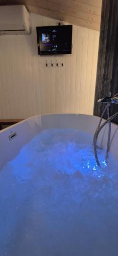 a tub filled with blue water in a room at Les Cocons d AleXan Le Chalet balnéo aromathérapie in Quinssaines