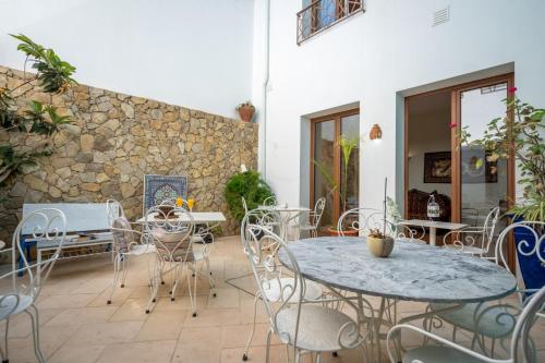 un patio con mesas y sillas y una pared de piedra. en Alvor Ar de Mar en Alvor