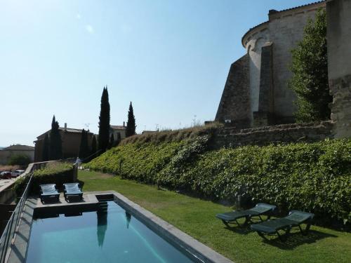 a swimming pool with two chairs and a building at Casa Marcial (adults only) in Besalú