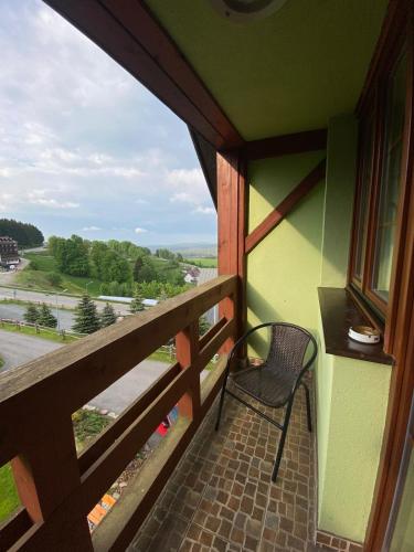 a balcony with a chair and a view of a road at Pod Orlicą in Duszniki Zdrój