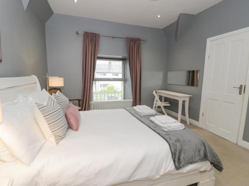 Un dormitorio con una gran cama blanca y una ventana. en Dale Cottage, en Llanrwst