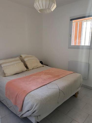 un lit dans une chambre blanche avec une fenêtre dans l'établissement Appartement en face mer, à Six-Fours-les-Plages