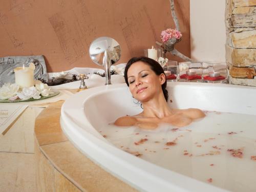 a woman laying in a bath tub at Wellness & Sporthotel Alpenhof in Ehrwald