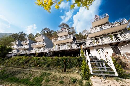 RāmgarhにあるKainchi Retreat near Kainchi Dhamの白いバルコニーのある丘の上の建物