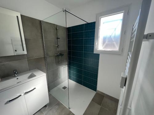 uma casa de banho com um chuveiro, um lavatório e uma porta de vidro em Maison neuve 4 etoiles à 10 minutes de Royan 