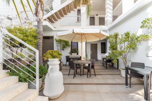 an outdoor patio with tables and chairs and an umbrella at Hotel Belvir in Villasimius