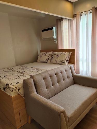 a bed with a couch in a room with a window at Studio Type BNB Accommodation in Bacolod