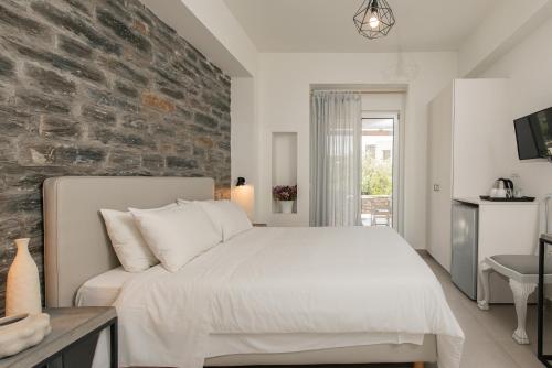 a bedroom with a white bed and a brick wall at Vourkari Village in Vourkarion