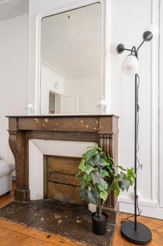 un miroir au-dessus d'une cheminée dans un salon avec une plante dans l'établissement Big apartment 2BR Arc de Triomphe 4-6p, à Paris