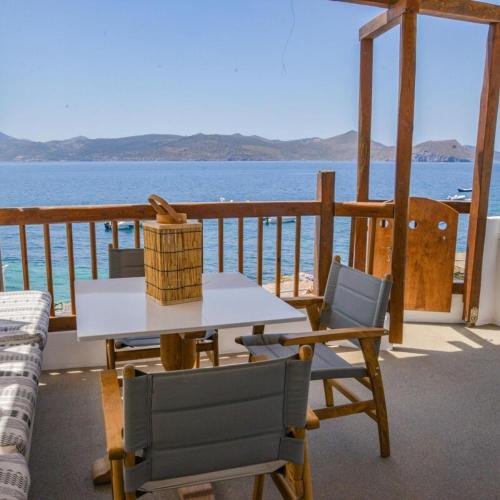 a table and chairs on a deck with a view of the ocean at honeymoon klima suite in Klima