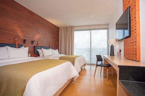 a hotel room with two beds and a television at voco Guadalajara Neruda by IHG in Guadalajara