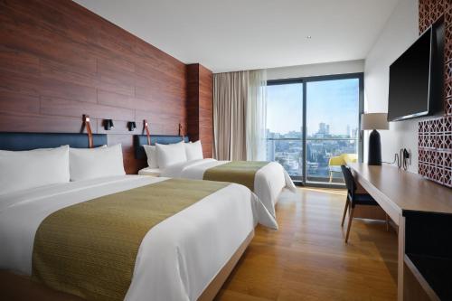 a hotel room with two beds and a desk at voco Guadalajara Neruda by IHG in Guadalajara