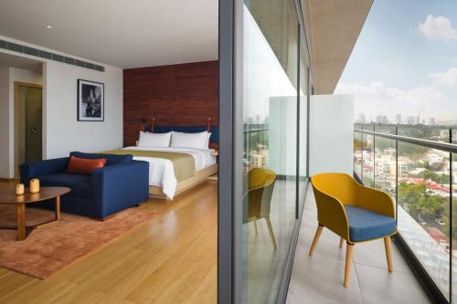 a hotel room with a bed and a chair at voco Guadalajara Neruda by IHG in Guadalajara
