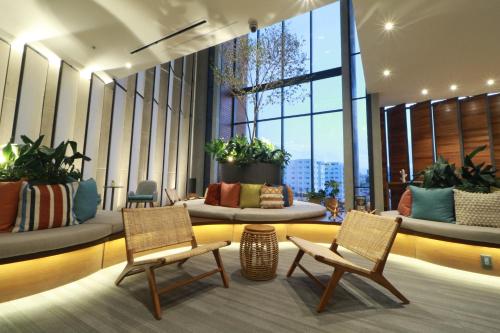 a lobby with two chairs and plants and windows at voco Guadalajara Neruda by IHG in Guadalajara