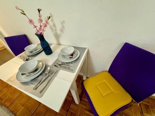 una mesa blanca con sillas y un jarrón con flores en Apartahotel Confort en Lausana