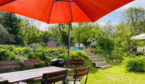 a picnic table with an umbrella in a garden at Ferienhaus Fiete XXL auf Rügen - Doppelferienhaus für 16 Personen in Sagard