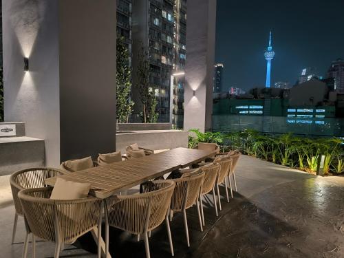 een houten tafel en stoelen op een balkon in de nacht bij Axon Apartment Bukit Bintang At KL in Kuala Lumpur