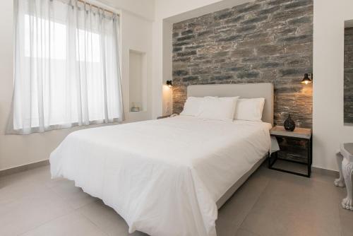 a white bed in a bedroom with a brick wall at Vourkari Village in Vourkarion