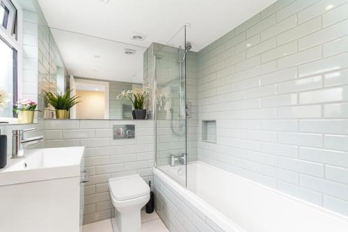 a bathroom with a tub and a toilet and a sink at Elegant Hither Green Family Home in London