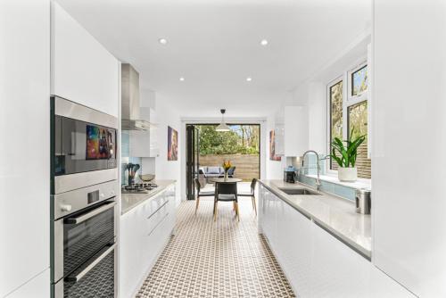 a kitchen with white appliances and a dining room at Elegant Hither Green Family Home in London