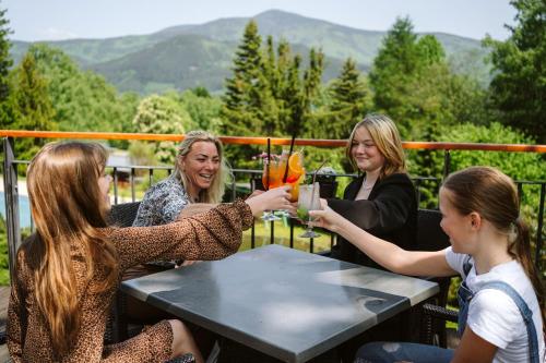 a group of women sitting around a table with drinks at Beltine Forest Hotel in Ostravice