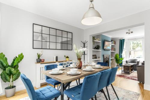 a dining room and living room with a wooden table and blue chairs at Elegant Hither Green Family Home in London