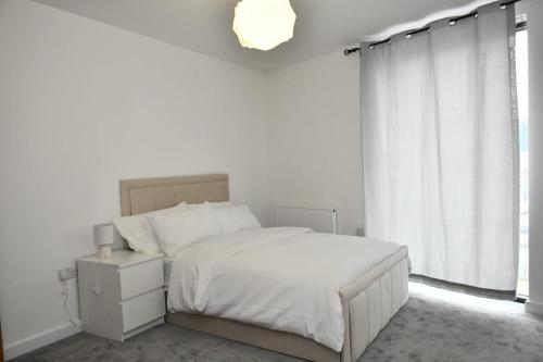 a white bedroom with a bed and a window at Spacious 2bedroom apartment in London city airport in London