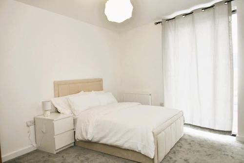 a white bedroom with a bed and a window at Spacious 2bedroom apartment in London city airport in London