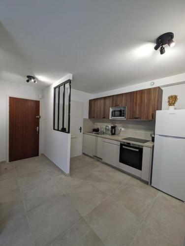 Il comprend une cuisine équipée d'un réfrigérateur blanc et d'une cuisinière. dans l'établissement 2 pièces lumineux à Cagnes sur mer, à Cagnes-sur-Mer