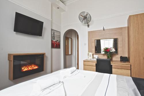 1 dormitorio con chimenea, 1 cama y TV en Linden House Hotel en Londres