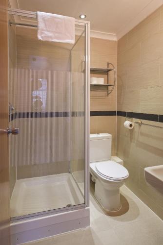 a bathroom with a toilet and a glass shower at Linden House Hotel in London