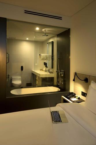 a bathroom with a bath tub and a bed with a remote control at Liberty Central Saigon Citypoint in Ho Chi Minh City
