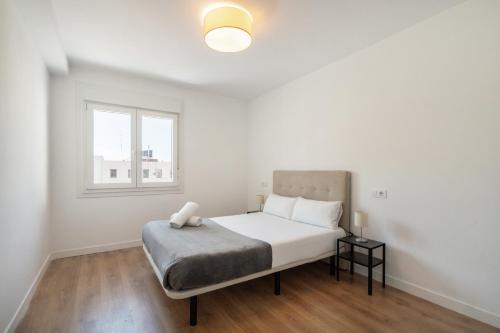 a white bedroom with a bed and a window at dobohomes - Fernandez de los rios in Madrid