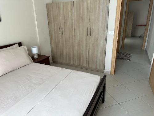 Schlafzimmer mit einem Bett und einem Holzschrank in der Unterkunft Sunny Coast Apartments in Sarandë