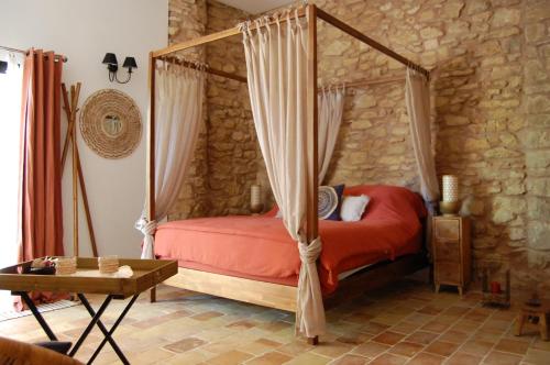 une chambre avec un lit à baldaquin et une table dans l'établissement La Bucolique, Chambres et Jardin d'Hôtes, à Sabran