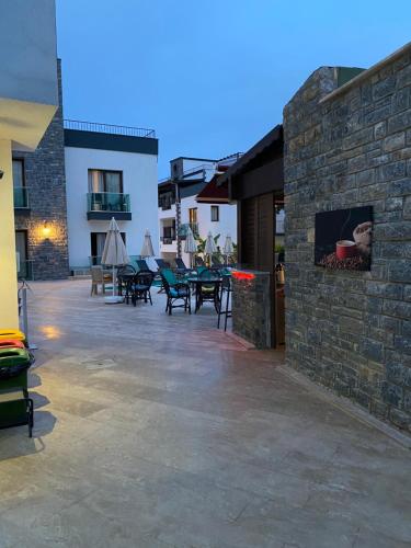 a patio with tables and chairs and a stone wall at Orya Aparts in Gümbet