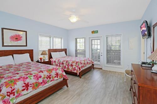 a bedroom with two beds and a dresser and windows at Big Chill by Pristine Property Vacation Rentals in Cape San Blas