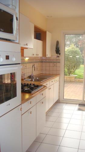 une cuisine avec des armoires blanches, un évier et une fenêtre dans l'établissement Le Repaire, à Saint-Coulomb