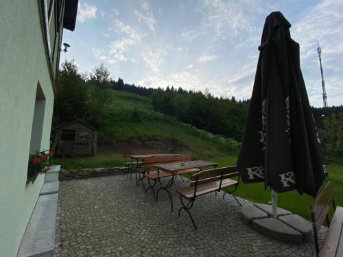 a patio with tables and an umbrella next to a building at Pod Orlicą in Duszniki Zdrój