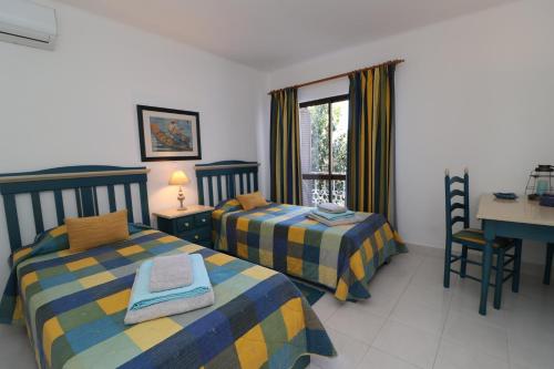 阿爾布費拉的住宿－Apt T2 Praia São Rafael Hibiscus 18A - Albufeira, Algarve，一间卧室设有两张床、一张桌子和一个窗口。