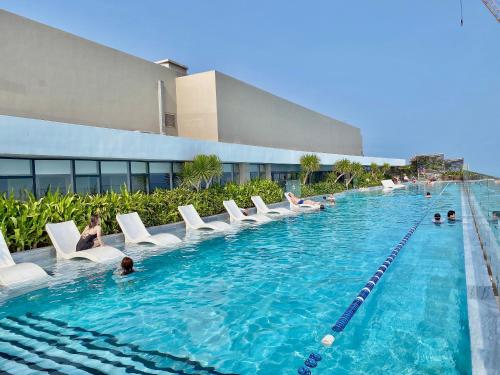 a swimming pool with white chairs and a building at The Sóng Vũng Tàu - An Gia Apartment in Vung Tau