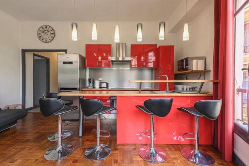 une cuisine avec des placards rouges et des tabourets de bar noirs dans l'établissement Charmant appt 3 chambes au coeur de Nice-5 mns plages, à Nice