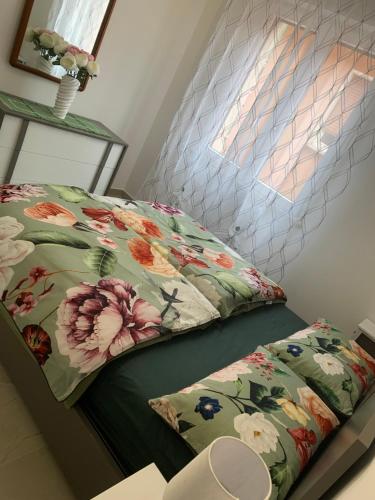 a bed with a floral pillow on it with a window at Appartamenti Estera 2 in Malcesine