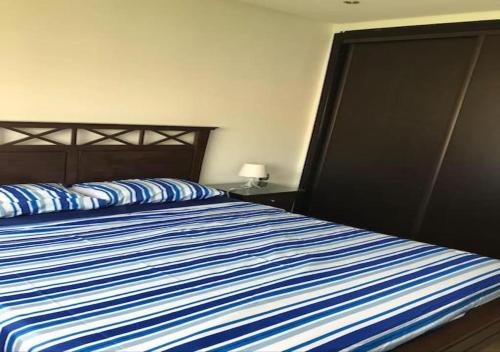 ein Schlafzimmer mit einem Bett mit einer blau-weißen gestreiften Bettdecke in der Unterkunft Appart Residence Haut Standing in Bouznika