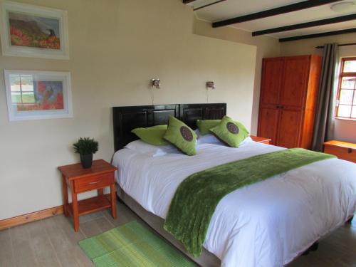 a bedroom with a large white bed with green pillows at Cottage Suikerbekkie in Dullstroom