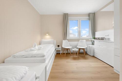 a white bedroom with two beds and a desk at Auszeit Borkum zentral & strandnah in Borkum