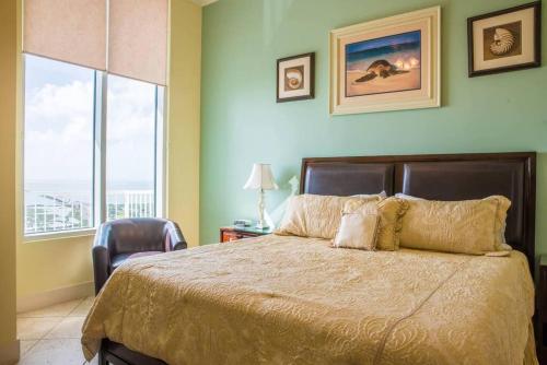 a bedroom with a bed and a chair and a window at 1901 Sapphire Beachfront 3 Bedroom Condo in South Padre Island
