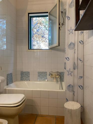 baño con bañera, aseo y ventana en Villa Lu, en Porto Cesareo